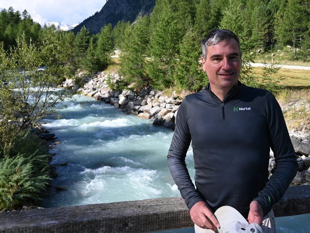 Florian steht auf einer Brücke über einen Bach in einem Tal.